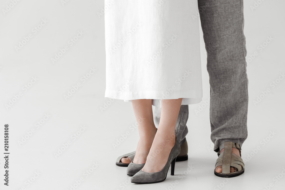 cropped image of legs of couple of models in linen dress and trousers isolated on grey background cropped image of legs of couple of models in linen dress and trousers isolated on grey background