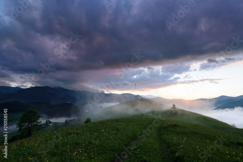 Scenery of the sunrise at the high mountains. Dense fog with beautiful light. The lawn with yellow flowers.