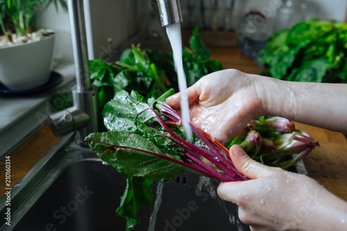 Woman washing fresh vegetables in kitchen
