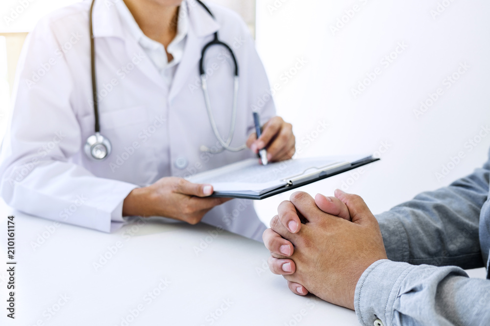 Doctor filling up an history form while consulting to patient and recommend treatment methods and how to rehabilitate