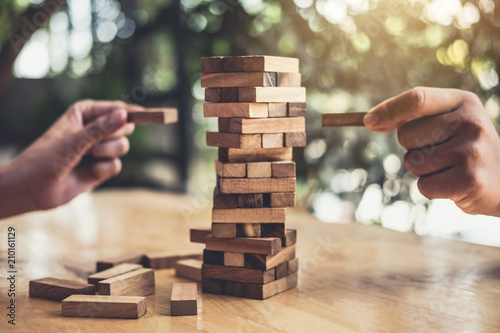 Hands of executive cooperation placing wood block on the tower, Collaborative management, Young intelligent businessman playing the wood game, Alternative risk concept, plan and strategy in business