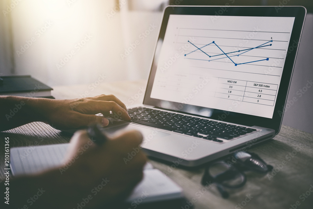 Naklejka premium Professional at work, businessman writing report and using laptop working analysis investment connection at modern workplace