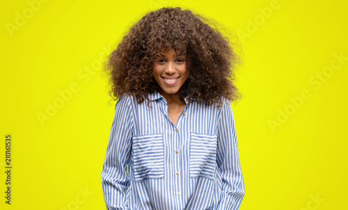 African american woman wearing a stripes shirt with a happy face standing and smiling with a confident smile showing teeth