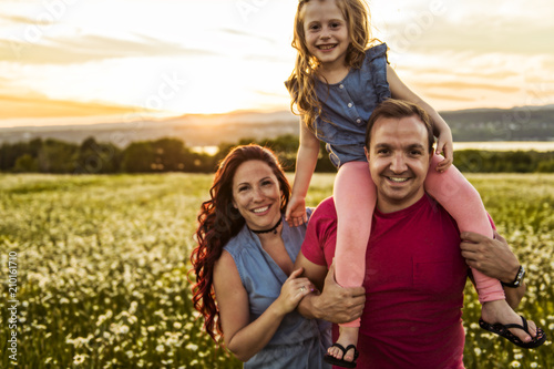 family outdoors spending time together Father, mother and daughter are having fun during the sunset.