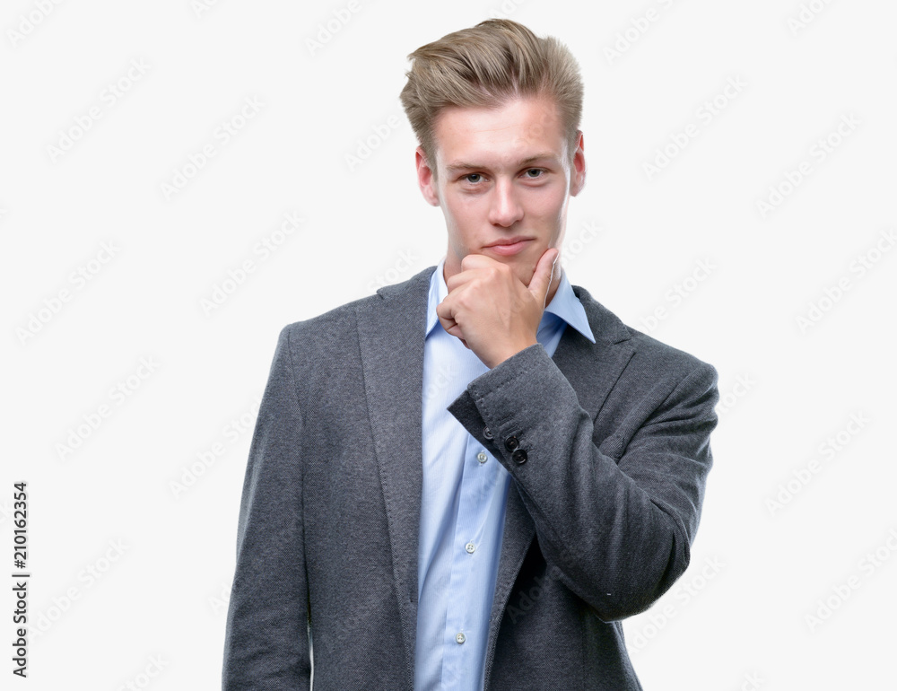 Young handsome blond business man looking confident at the camera with smile with crossed arms and hand raised on chin. Thinking positive. Young handsome blond business man looking confident at the camera with smile with crossed arms and hand raised on chin. Thinking positive.