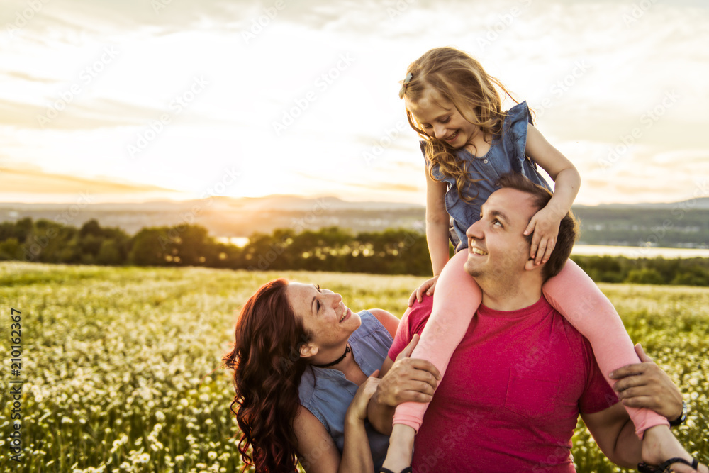 family outdoors spending time together Father, mother and daughter are having fun during the sunset.