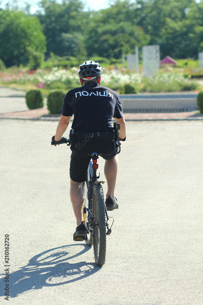 Obraz premium Policeman patrolling park on bicycle in new summer uniform.