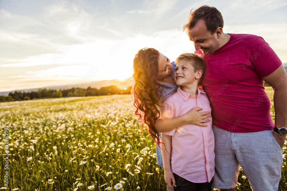Happy family having fun on daisy field at sunset