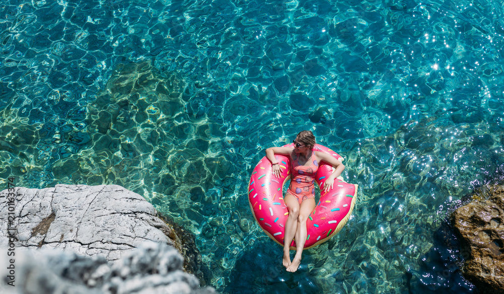 A Woman Floating on Doughnut Ring on Turquoise Sea