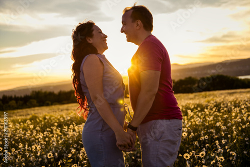 Man and woman on the daisy field at sunset