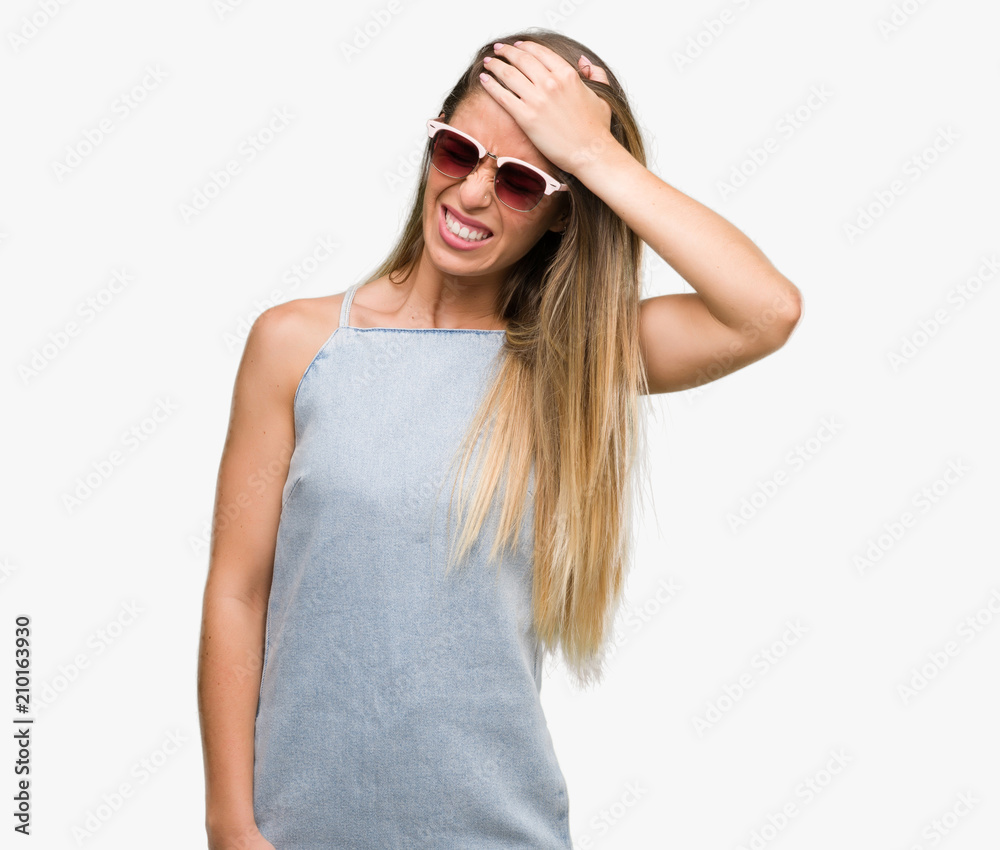 Beautiful young woman wearing sunglasses and denim dress stressed with hand on head, shocked with shame and surprise face, angry and frustrated. Fear and upset for mistake.