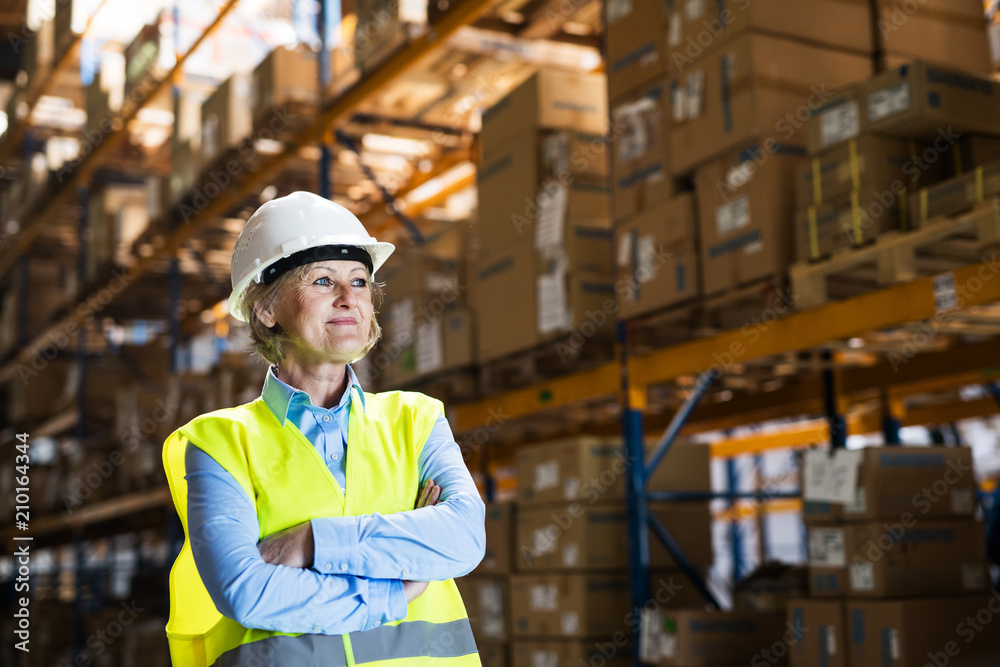 Senior woman manager or supervisor standing in a warehouse, arms crossed. Senior woman manager or supervisor standing in a warehouse, arms crossed.