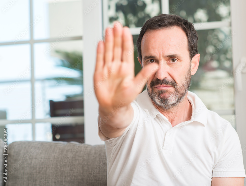 Handsome middle age man with open hand doing stop sign with serious and confident expression, defense gesture Handsome middle age man with open hand doing stop sign with serious and confident expression, defense gesture