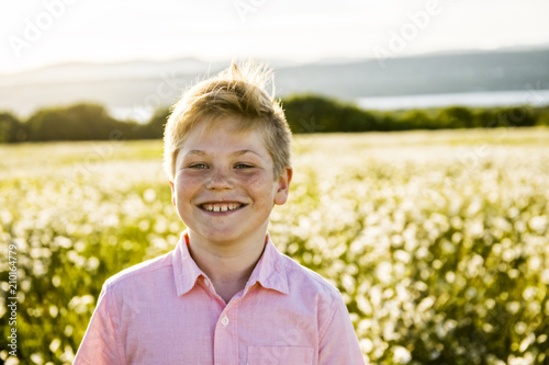 boy on meadow of daisies flowers at the sunset