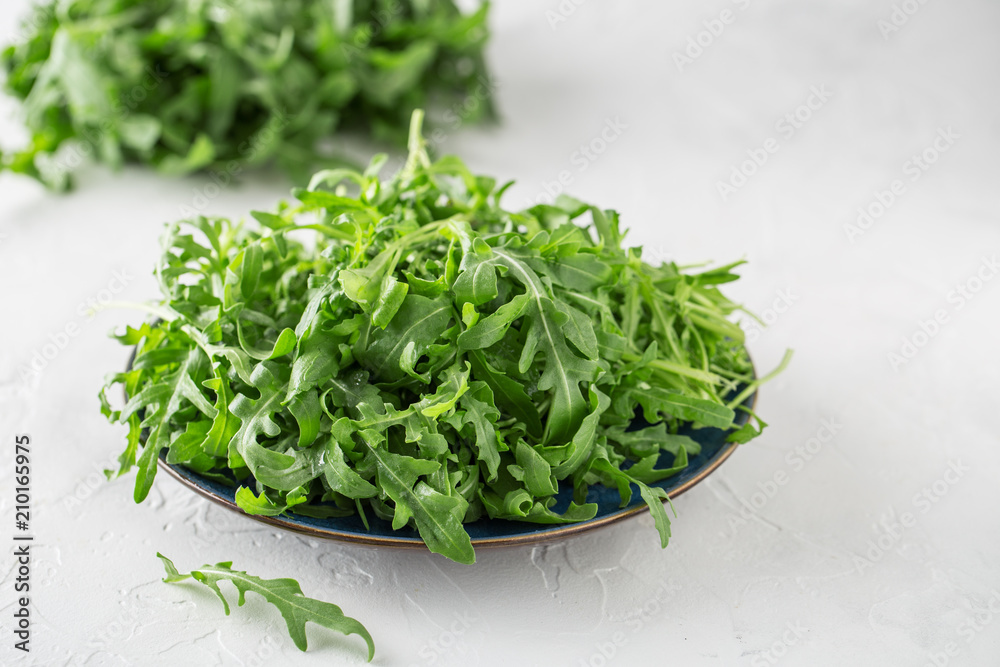 Fresh green arugula in bowl on table. Arugula rucola for salad. Close up of fresh green healthy food. Diet concept Fresh green arugula in bowl on table. Arugula rucola for salad. Close up of fresh green healthy food. Diet concept