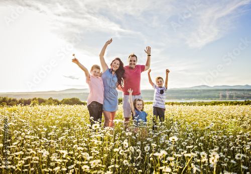 Happy family having fun on daisy field at sunset