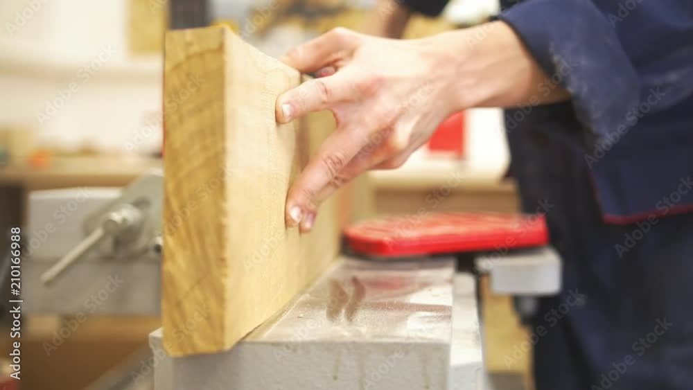 Carpenter male hands polishing wooden plank using industrial carpentry equipment in workshop Carpenter male hands polishing wooden plank using industrial carpentry equipment in workshop