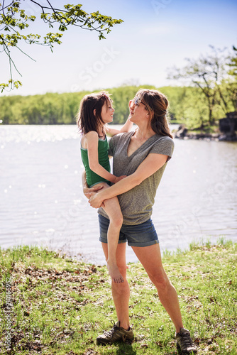 Mother standing by a lake carrying her daughter
