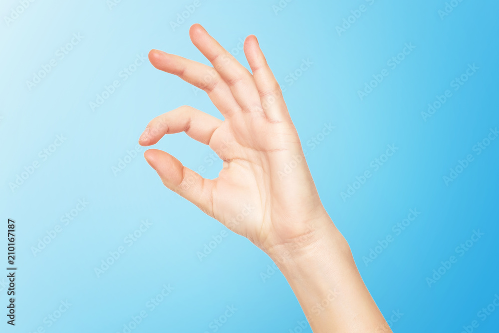 Closeup female hand making OK gesture isolated at blue background.