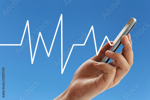 Hand of the businessman hold a smartphone with Line graph in business concept on blue background.