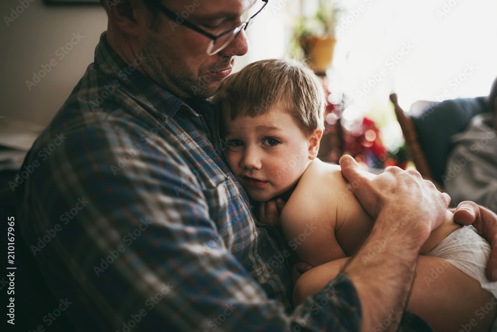 Father Sitting On Couch Cuddling His Son And Kissing Him On The Head Foto De Stock Adobe Stock