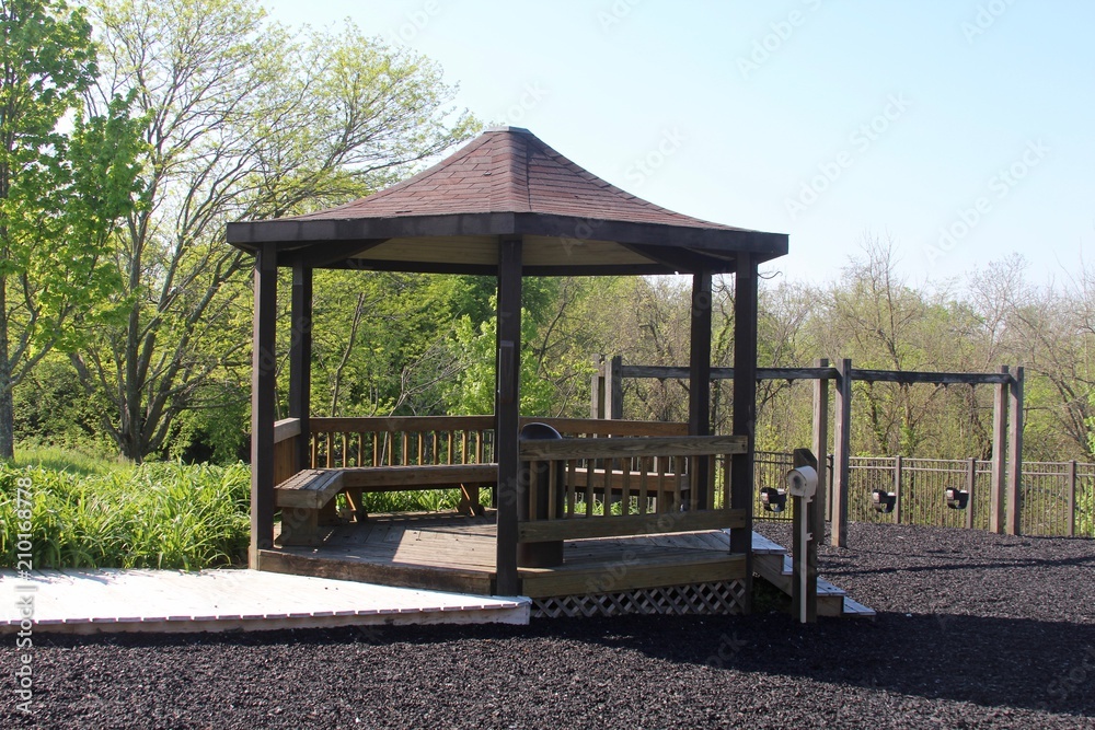 A wooden gazebo in the park on a sunny spring day. 
