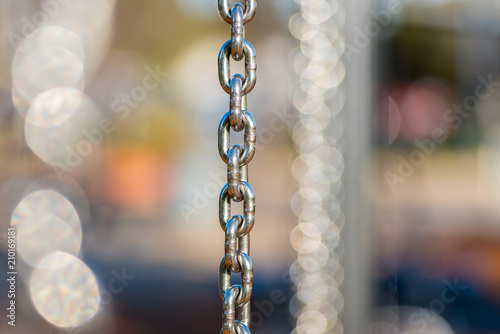 Many vertical hanging stainless steel chains in varying depth of field and focus