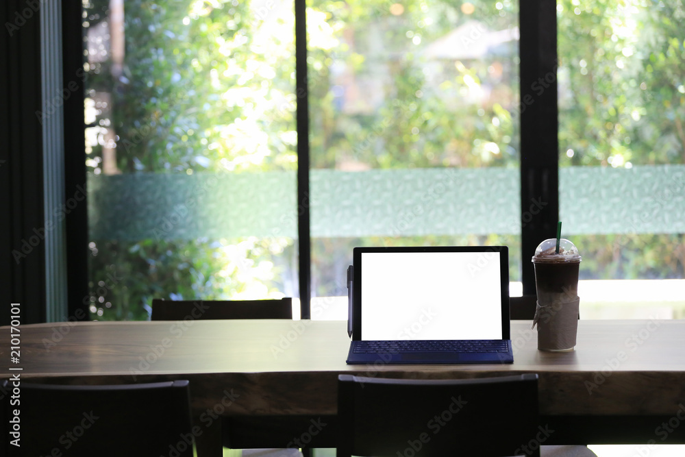 Empty screen of laptop and cold coffee mug placed on a food table in a coffee shop. Empty screen of laptop and cold coffee mug placed on a food table in a coffee shop.