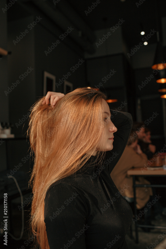 Young girl with long red hair sitting in café Young girl with long red hair sitting in café