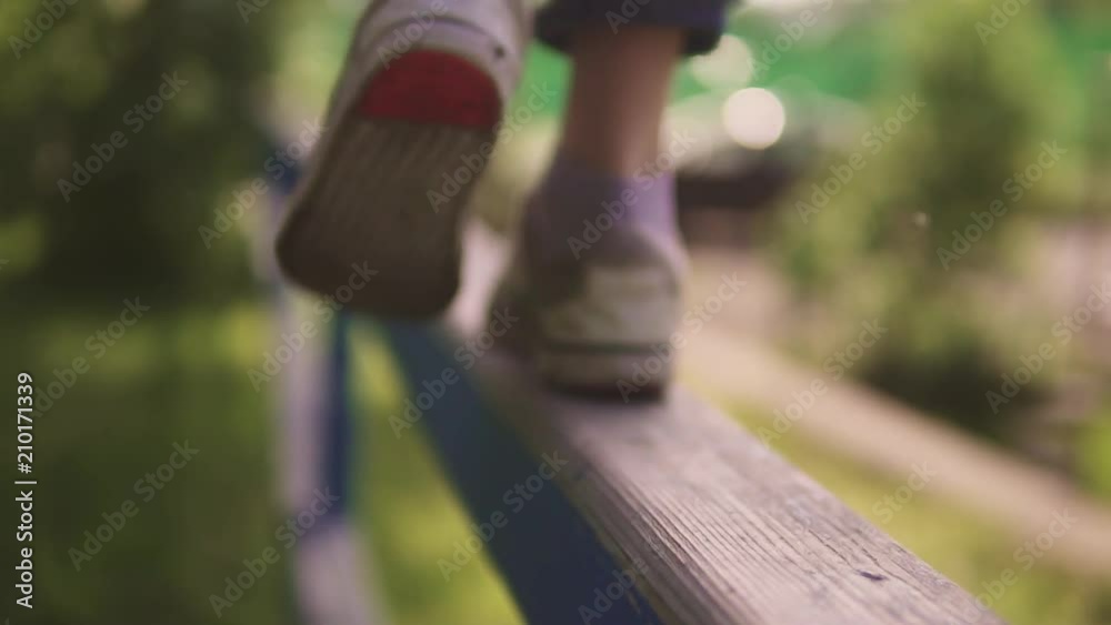 children's legs close-up. the child is on the crossbar and balances in the air. the concept of a happy and serene childhood. slow motion