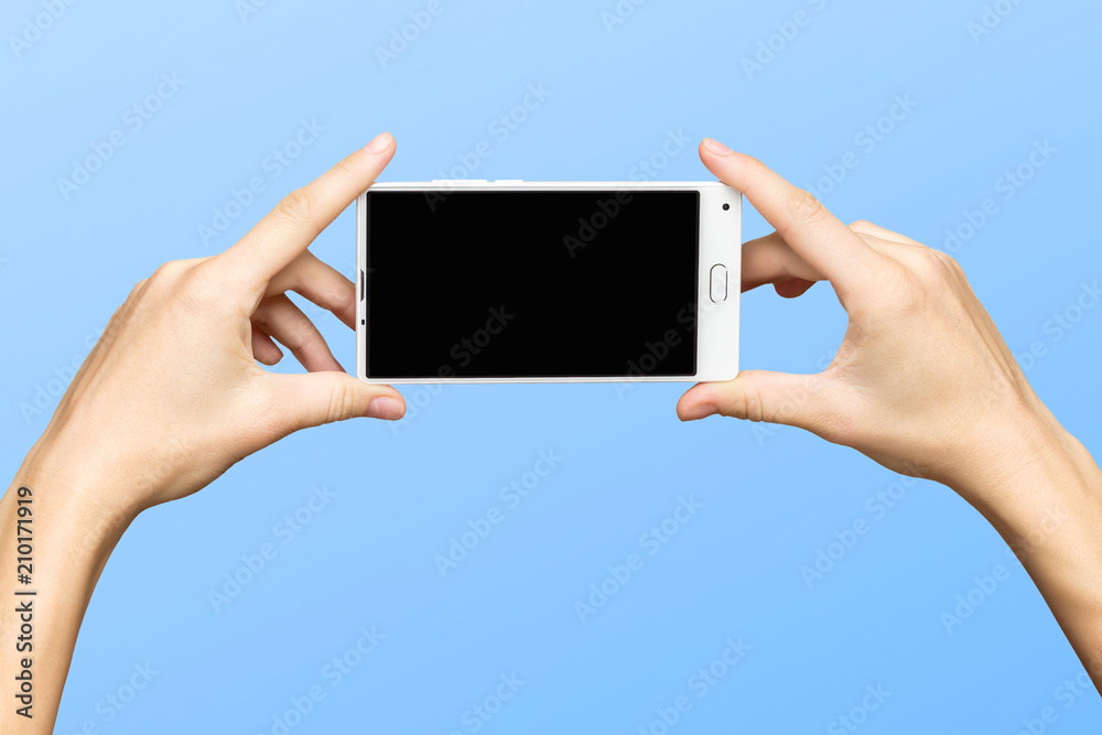 Mockup of female hands holding new frameless smartphone with black screen at isolated blue background.