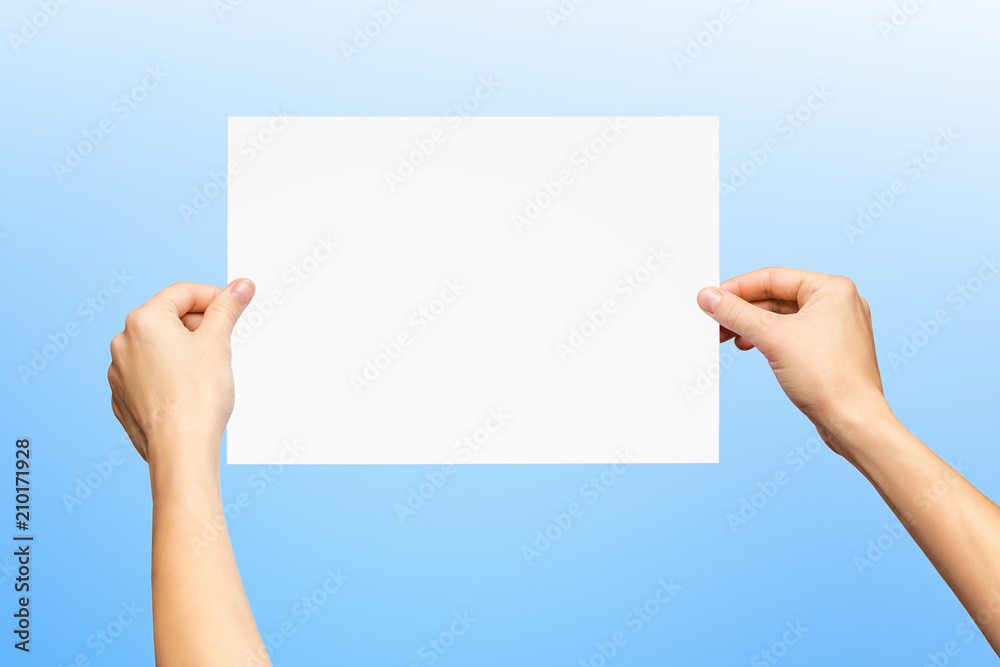 Mockup of female hands holding blank paper list isolated at blue background. Mockup of female hands holding blank paper list isolated at blue background.