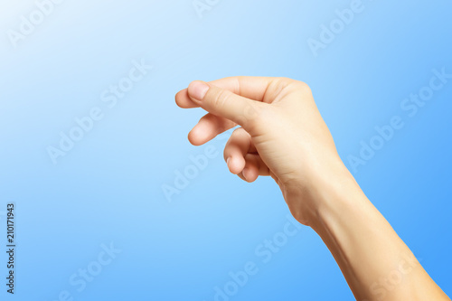 Closeup empty female hand holding invisible business card isolated at blue background.