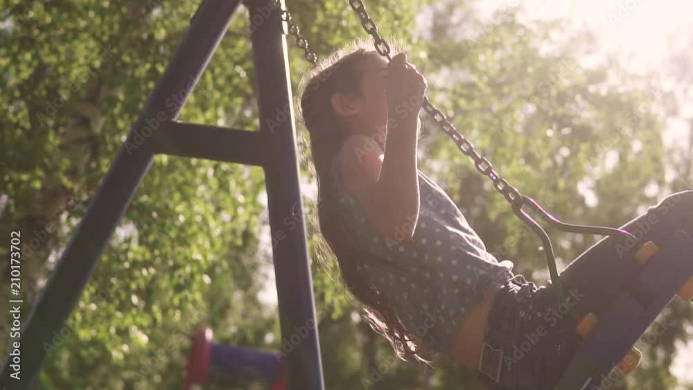 happy child swinging on a swing and enjoying a beautiful summer day. concept of joy and happy childhood