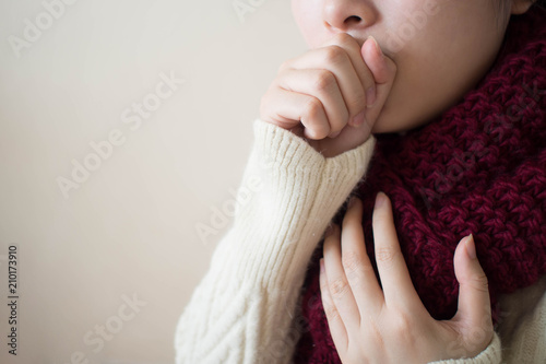 Young ill female have a cough and sore throat in winter. Causes of cough include common cold, flu, respiratory tract infection, pneumonia, bronchitis, allergy, asthma or COPD. Copy space. Health care. photo