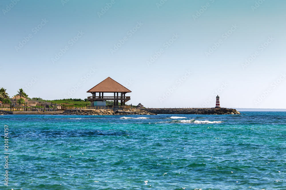 Bungalow and a lighthouse on the seashore
