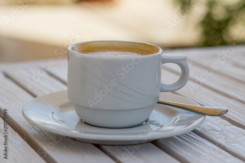 white cappuccino cup on a white wooden table on a sunny summer