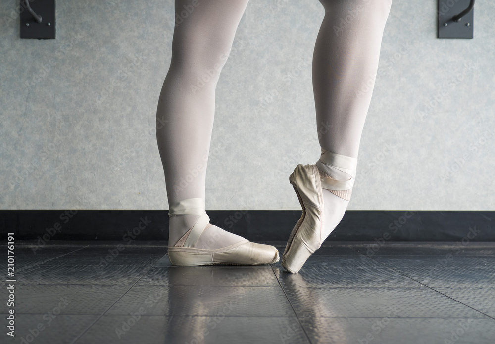 Ballet dancer warming up her feet in her pointe shoes for ballet class Ballet dancer warming up her feet in her pointe shoes for ballet class
