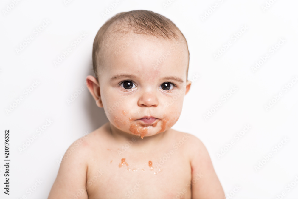 Happy infant baby boy doing a mess eating puree Happy infant baby boy doing a mess eating puree