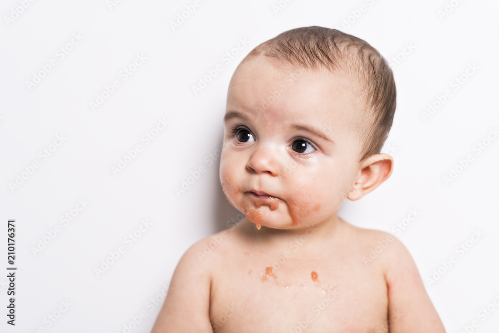 Happy infant baby boy doing a mess eating puree Happy infant baby boy doing a mess eating puree