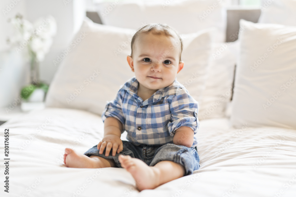Adorable baby boy in white bedroom in morning