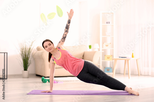Beautiful young woman practicing yoga at home in morning