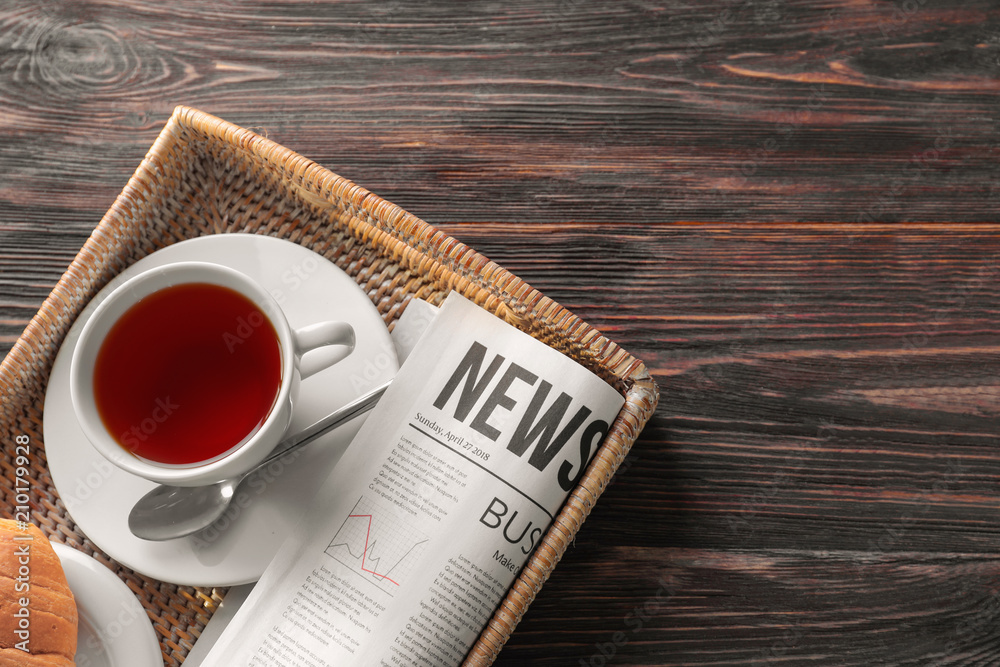 Tray with newspaper and cup of tea on wooden background Photos | Adobe Stock