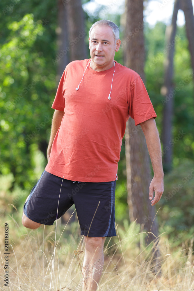 Fototapeta premium mature male athlete runner stretching in the forest