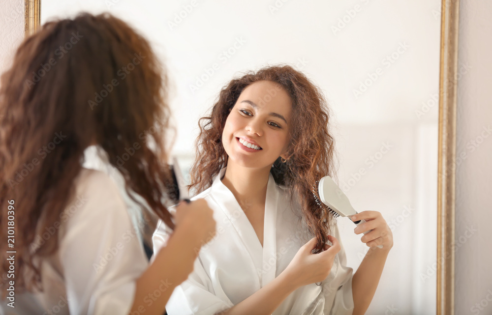 Morning of young African-American woman brushing hair near mirror Morning of young African-American woman brushing hair near mirror