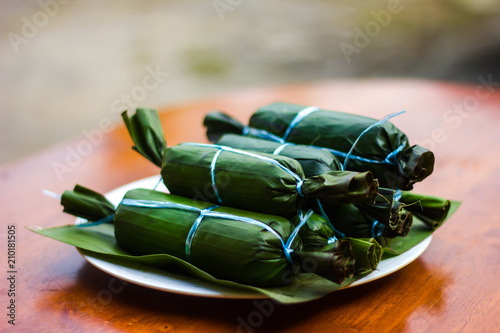 Closeup shot of Ketupat Daun Pisang on wooden table in blur background . Malaysian cuisine