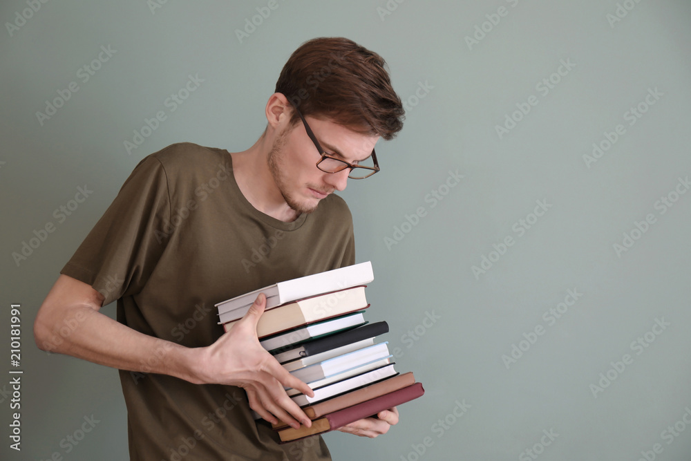 Young man with stack of books on color background Young man with stack of books on color background