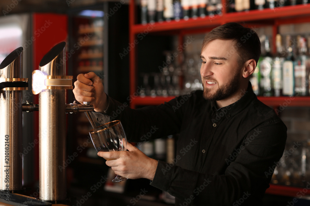 Bartender pouring beer into glass in bar
