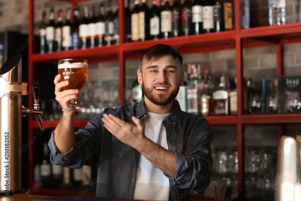Bartender with glass of beer in bar Bartender with glass of beer in bar