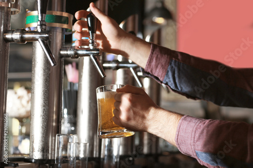 Bartender pouring beer into glass in bar